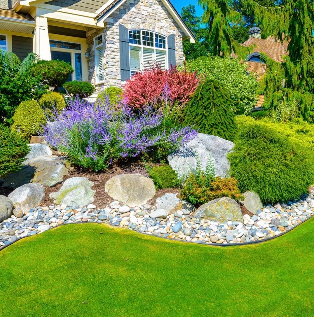 Landscaped front yard with lawn, shrubs, decorative rock and planting beds